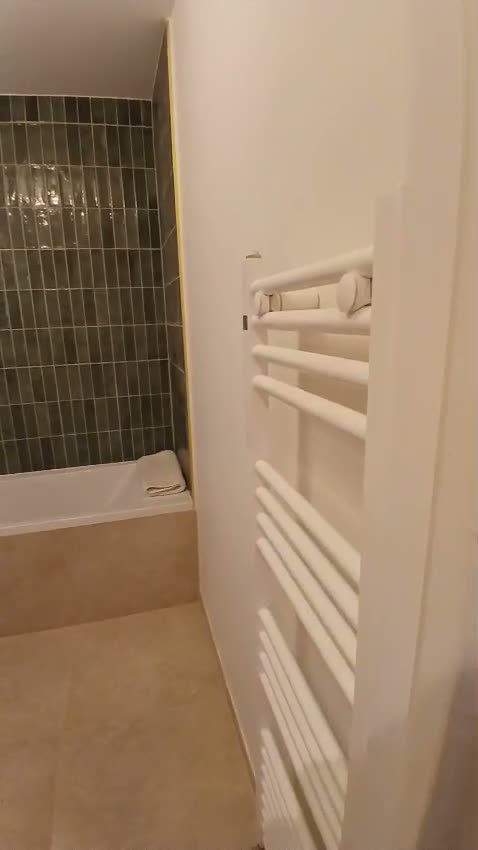 Salle de bains finie à Paris 17e : baignoire, carrelage vertical et sèche-serviettes
