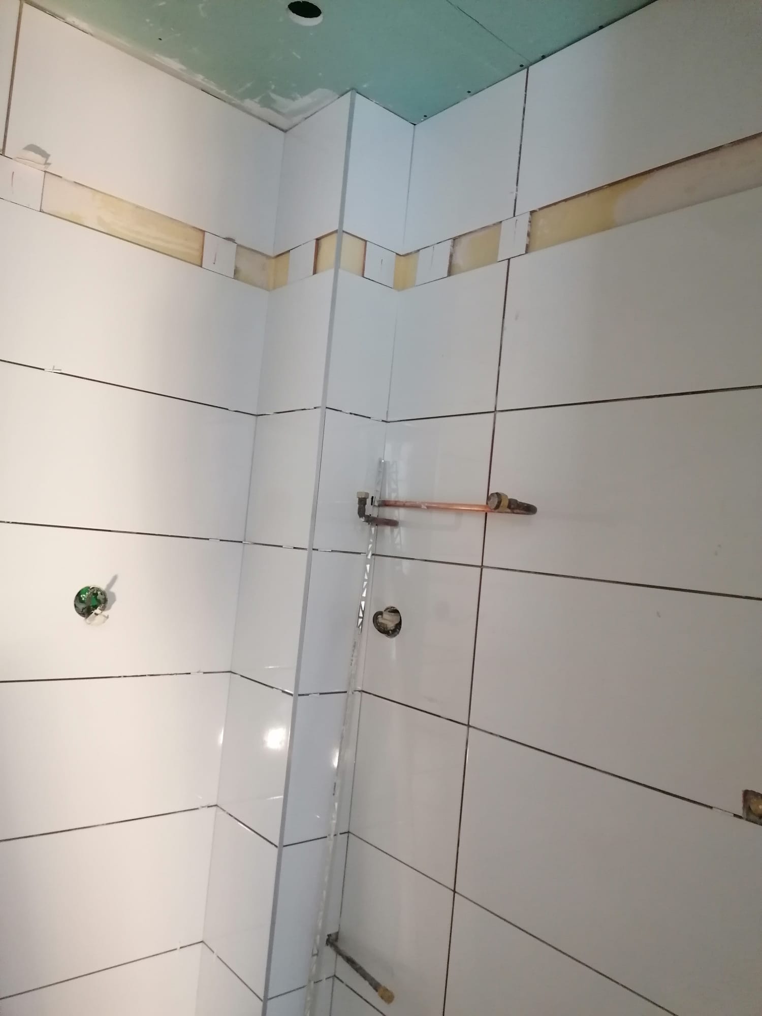 Faïence blanche posée dans la douche avec alimentations en cuivre en attente