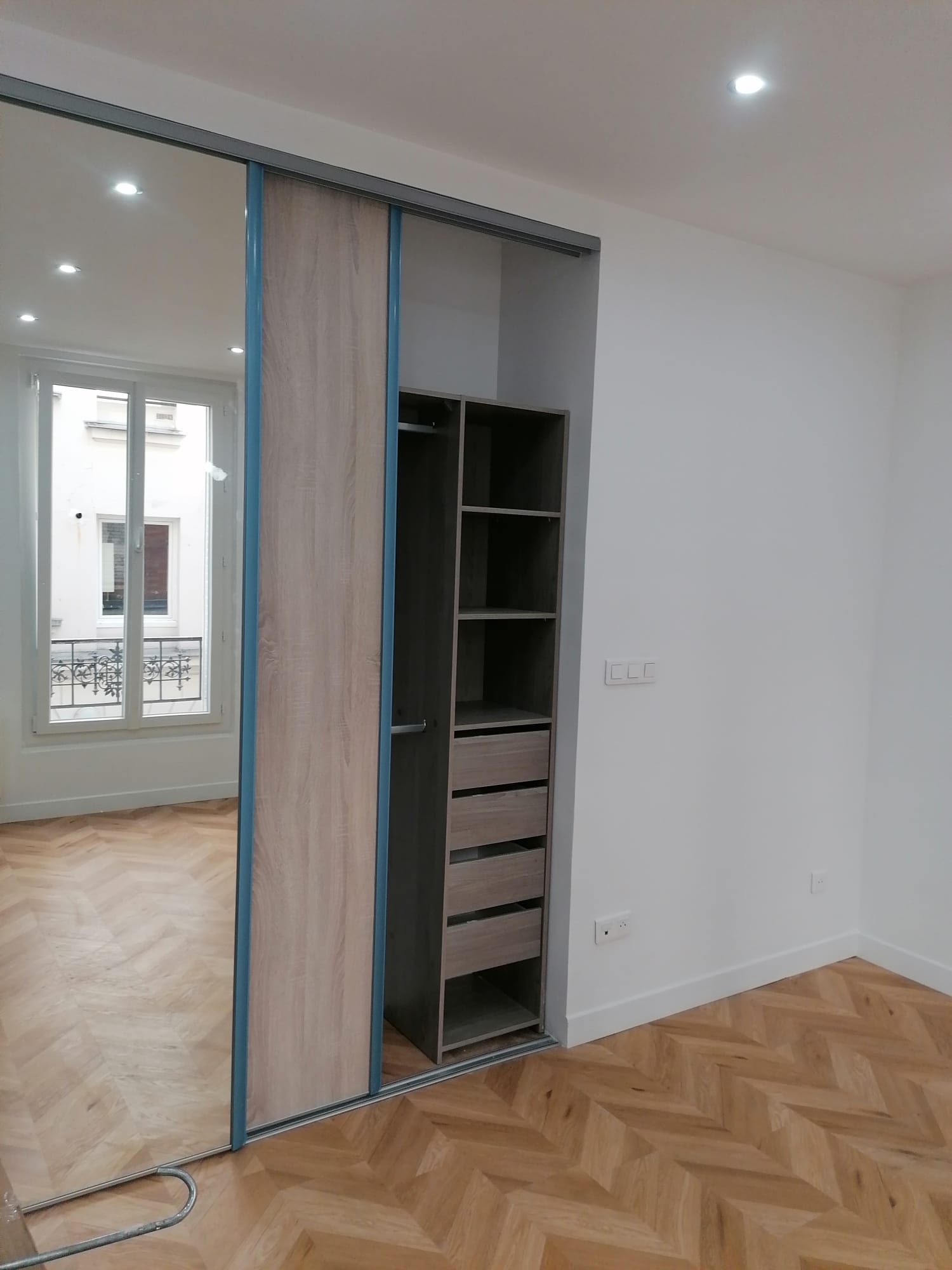 Placard sur mesure à portes coulissantes miroir et parquet chevron à Paris 8e