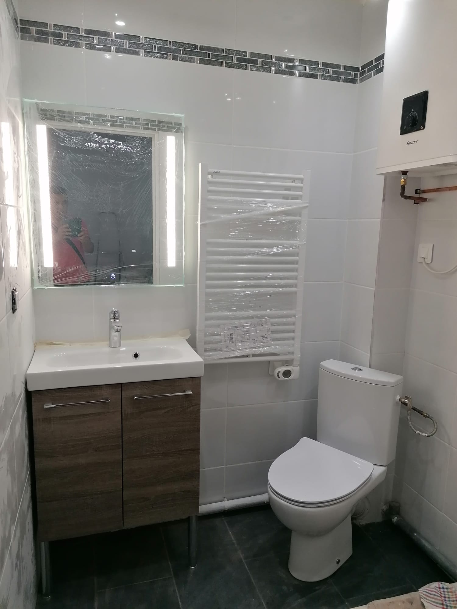 Salle d'eau rénovée : meuble vasque, miroir rétro-éclairé, sèche-serviettes et WC