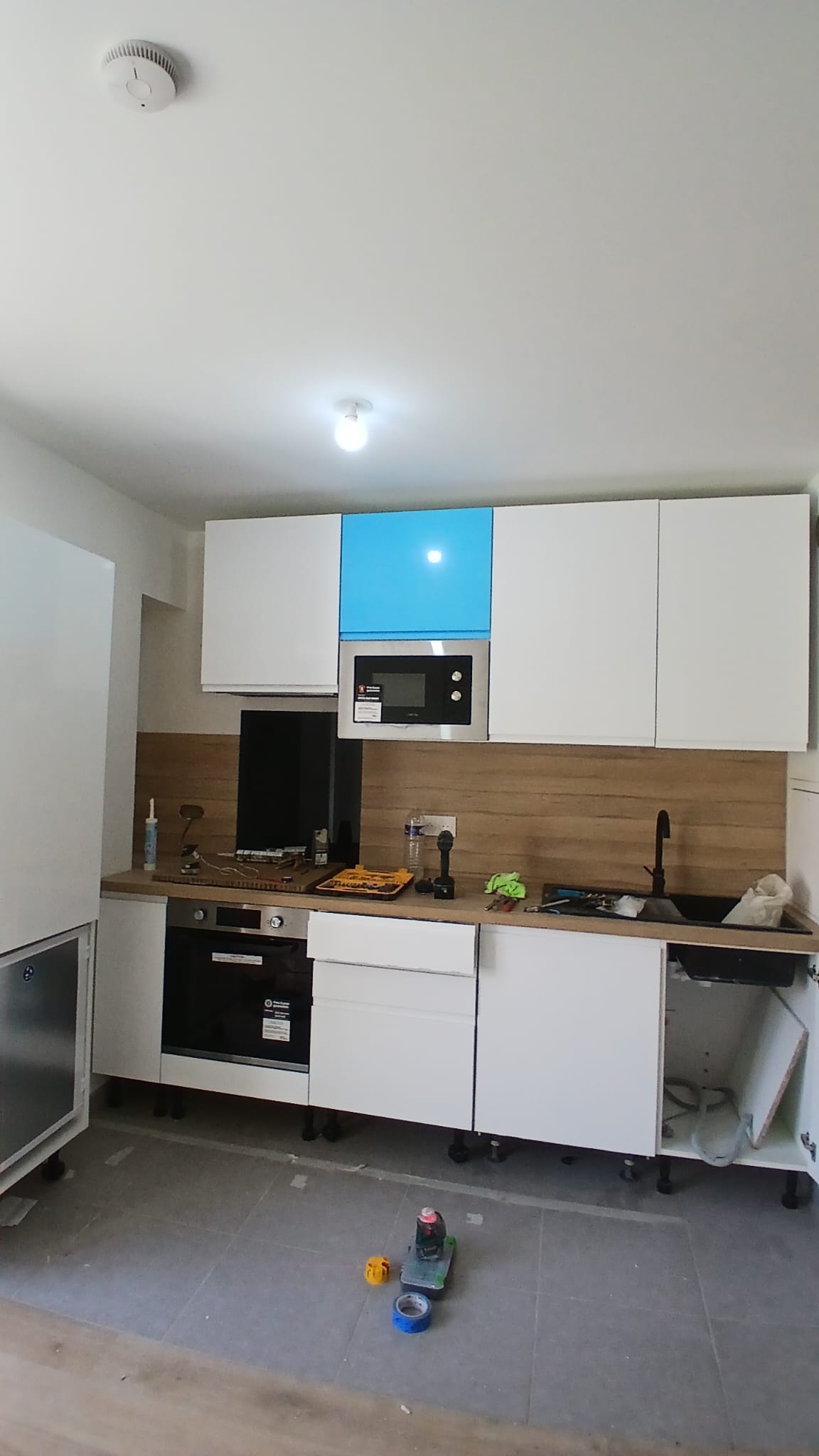Vue frontale de la cuisine : électroménager encastré, plan de travail bois et finitions blanches