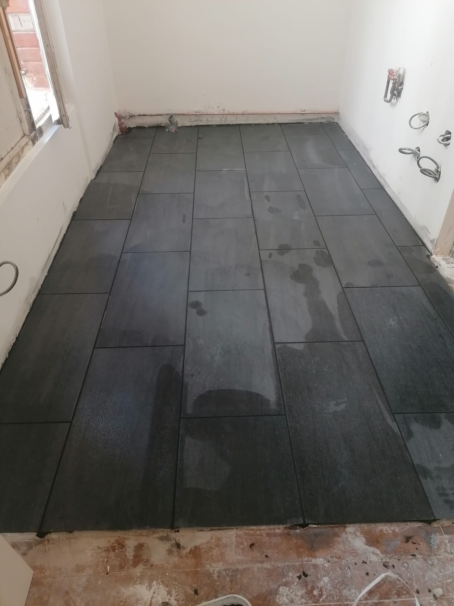 Carrelage grès cérame gris grand format posé au sol dans la pièce en travaux